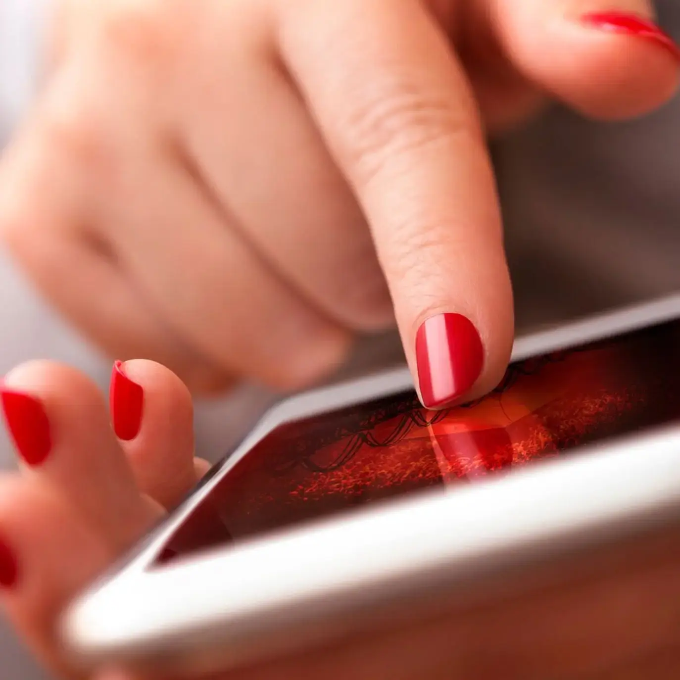 Womans hand holding a phone red nails